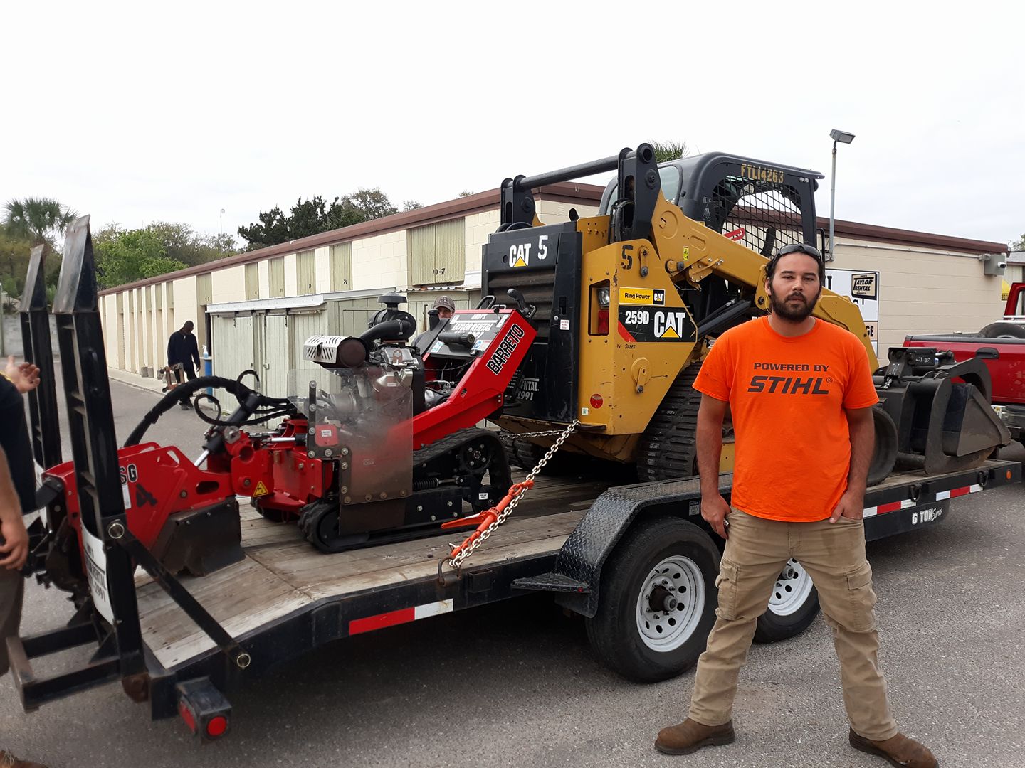 worker posing in front of stump grinder